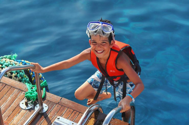 child coming out water wearing life jacket